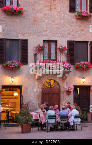 Groupe de touristes appréciant un repas du soir à la terrasse d'un café à Pienza, Toscane Italie Banque D'Images