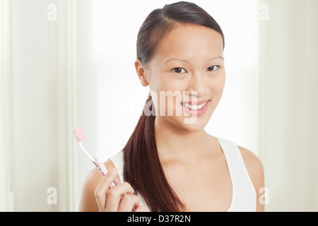 Femme tenant une brosse à dents dans la salle de bains Banque D'Images