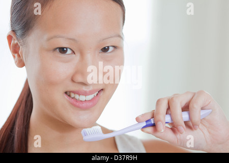 Femme tenant une brosse à dents dans la salle de bains Banque D'Images