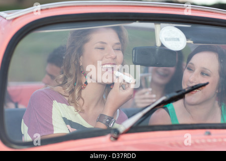 Woman applying lipstick in convertible Banque D'Images