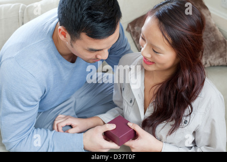 Man giving girlfriend gift on sofa Banque D'Images