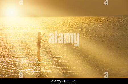 USA, North Carolina, Nags Head, Man Standing on paddle board au coucher du soleil Banque D'Images