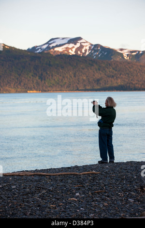 Tourist photographing Kachemak Bay au coucher du soleil de Homer Spit, Homer, Alaska, USA Banque D'Images