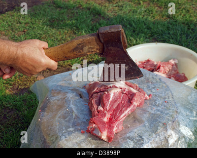 Couper la viande avec une hache sur une cale en bois Banque D'Images