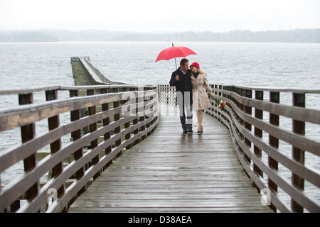 Couple en train de marcher sur la jetée en bois dans la pluie Banque D'Images