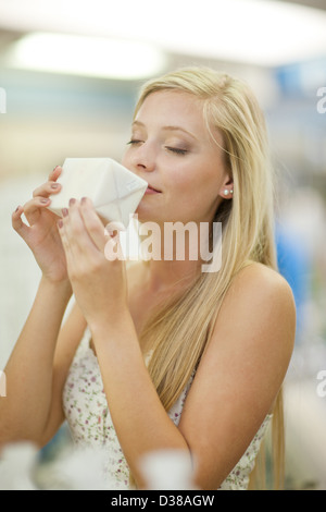 Woman smelling candle in store Banque D'Images