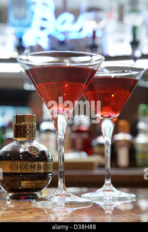 Deux verres à cocktail sur un bar avec une bouteille de Chambord, une liqueur de framboise noire. Banque D'Images