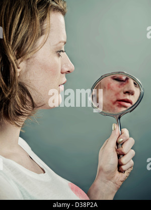 L'examen de son visage meurtri Femme Banque D'Images