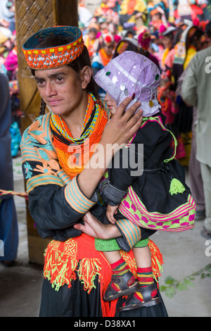 Kalash femme portant sa jeune fille à la Kalash Joshi (Fête du Printemps), Village Grum Charso (danse), de la vallée de Rumbur, Chitral, Khyber-Pakhtunkhwa, Pakistan Banque D'Images