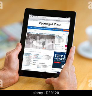 La lecture de l'édition en ligne du New York Times sur un 4ème génération d'Apple iPad, USA Banque D'Images