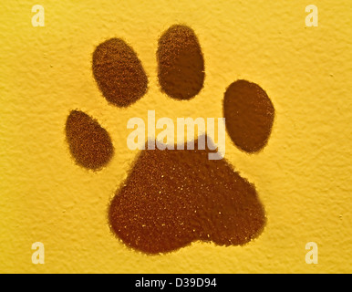 Il s'agit d'une empreinte de patte animal brun peint sur un mur de couleur jaune, dans un format horizontal. Banque D'Images