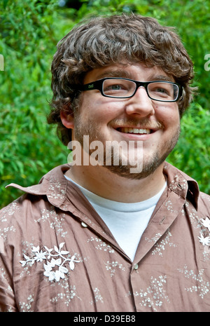Les jeunes adultes de sexe masculin est de race blanche au début de la vingtaine, dans ce portrait en extérieur. Il porte des lunettes cerclées de noir. Banque D'Images