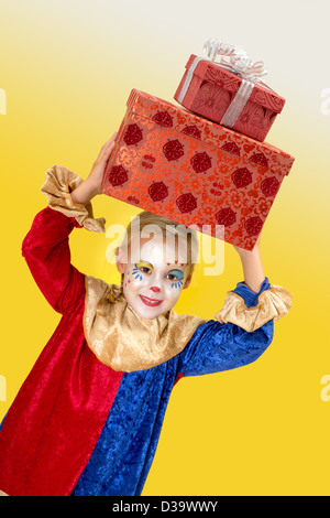 Smiling girl clown avec de grands présente sur sa tête Banque D'Images