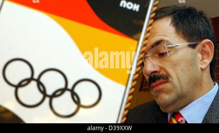 (Afp) - Klaus Steinbach, président de la Comité National Olympique (CNO), est assis derrière un drapeau qui montre les couleurs nationales allemande et les anneaux olympiques, au cours d'une conférence de presse de la CNP à Francfort, 11 novembre 2003. La ville de Leipzig a demandé à accueillir les Jeux Olympiques de 2012. Banque D'Images