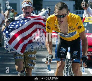 (Afp) - Un ventilateur avec un drapeau américain suit Lance Armstrong de l'équipe US Postal au cours de la 12e étape du Tour de France à partir de Lannemezan à plateau-de-Beille, dans la région de Lannemezan, 19 juillet 2002. Banque D'Images