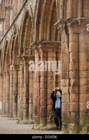 Un homme prend une photo dans le reste de l'abbaye de Jedburgh, ruines d'Abbaye Augustinienne du 12ème siècle dans les Scottish Borders Banque D'Images