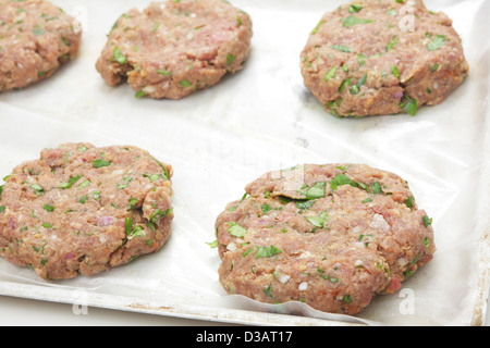 Beeburger brut huilé de boeuf haché sur un papier sulfurisé sur une plaque de cuisson Banque D'Images