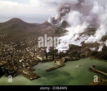 (Dpa) - cendres noires couvrent la ville de Vestmannaeyjar sur l'île Heimaey, l'Islande, en photo plusieurs mois après l'éruption du volcan en 1973. Dans l'arrière-plan et les nouveaux fumeurs encore Kirkjufjell volcan ('church mountain', R), et sur la gauche le volcan éteint, Helgafjell ('ho Banque D'Images