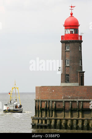 (Afp) - un bateau de pêche passe le phare à l'extrémité de la jetée du Nord à l'entrée du port d'Geestevorhafen à Bremerhaven, Allemagne, 16 juin 2005. Banque D'Images