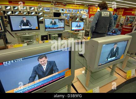 (Afp) - Un client d'un escompteur d'électronique surveille le session du Bundestag concernant le vote de confiance pour le chancelier allemand Gerhard Schroeder sur plusieurs écrans à Hambourg, Allemagne, 1 juillet 2005. Banque D'Images