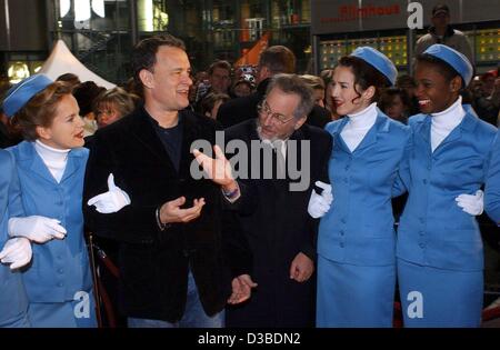 (Afp) - L'acteur américain Tom Hanks (L) et réalisateur américain Steven Spielberg posent avec des hôtesses de l'avant de la première Allemande de leur nouveau film "Arrête-moi si tu peux" à Berlin, le 26 janvier 2003. Le film, basé sur une histoire vraie, est sur la réussite d'un artiste qui parvient à se faire passer pour plusieurs ident Banque D'Images