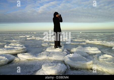 (Afp) - Une femme se tient sur la glace et prend des photos du paysage de glace près de Wismar, Allemagne, le 9 janvier 2003. Banque D'Images
