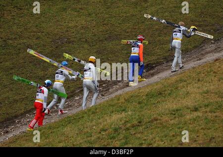 (Afp) - Les cavaliers portent leurs skis Ski montée à travers un champ vert jusqu'à l'Olympia Schanze lors d'une formation pour les quatre tournois Hill à Garmisch-Partenkirchen, Allemagne, 31 décembre 2002. Banque D'Images