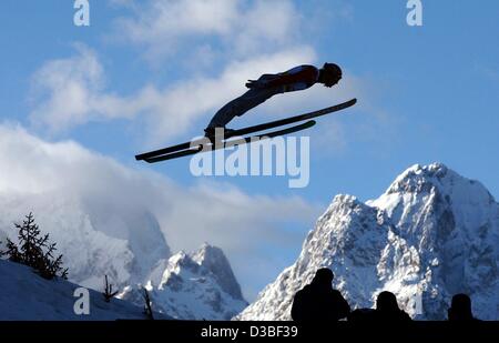 (Afp) - un cavalier ski vole dans l'air en face d'une vue panoramique sur la Zugspitze et enneigés des montagnes Waxenstein, lors d'un saut de la colline de saut olympique (Olympia Schanze) à Garmisch-Partenkirchen, Allemagne, 1 janvier 2003. Banque D'Images
