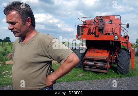 (Afp) - Agriculteur Jerzy Kopaszewski est pensif en face de ses 20 ans, moissonneuse-batteuse, sur sa ferme de Boleszkowice, Pologne, 24 juin 2003. Kopaszewski exploite sa ferme indépendante depuis huit ans maintenant, et a un moment difficile de nourrir sa famille de six. Il a voté contre l'adhésion à t Banque D'Images