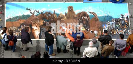 (Afp) - Les passants par examiner le tableau d'un artiste de rue dans le centre commercial du centre-ville de Munich, Allemagne, 22 mai 2003. La peinture est plusieurs mètres carrés et présente une variété d'animaux de partout dans le monde. Le dernier tiers est en attente d'être terminé. Banque D'Images