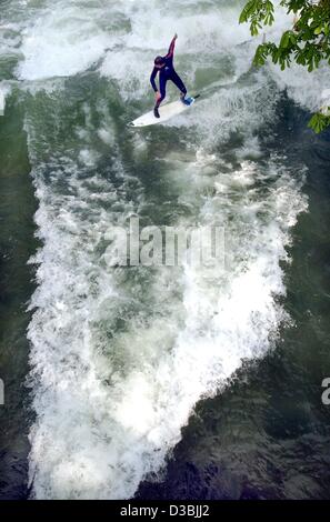 (Afp) - un surfeur sur sa planche glisse sur une vague de l'Eisbach Creek dans le Jardin Anglais de Munich, 22 avril 2003. Banque D'Images