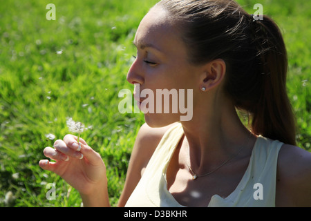 Girl enjoying summertime à une pelouse de pissenlits Banque D'Images