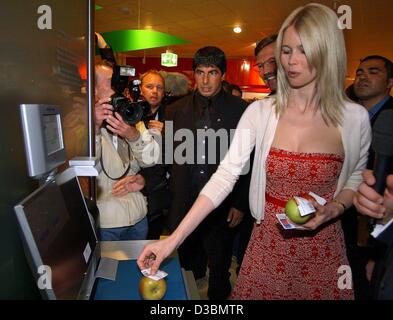 (Afp) - Le top model allemand Claudia Schiffer (R) pèse une pomme dans le premier supermarché du futur métro à Rheinberg, Allemagne, 28 avril 2003. Derrière elle se tient Hans-Joachim Koerber (en partie couverte), Président du Conseil de l'groupe grossiste allemand METRO AG. Plusieurs nouvelles technologies sont testés dans Banque D'Images