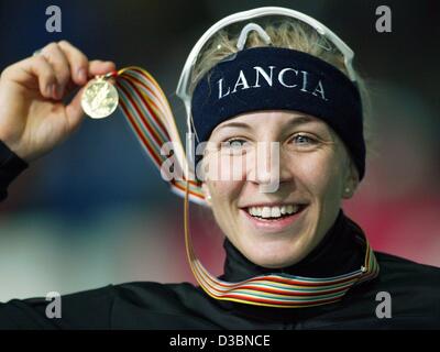 (Afp) - La patineuse de vitesse Allemande Anni Friesinger sourires et gestes et présente sa médaille après l'accélération en bas de la piste de glace dans le women's 1500 mètres au Championnat du monde de patinage de vitesse à Berlin, le 14 mars 2003. Friesinger exécute la distance en 1:57,43 minutes et remporte le titre de champion du monde. Banque D'Images