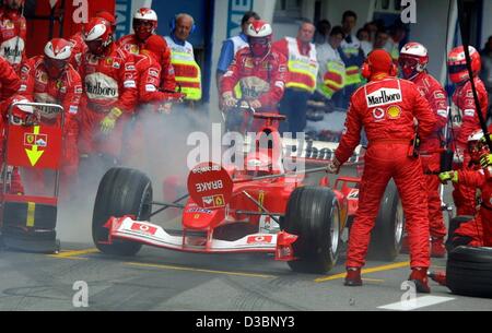 (Afp) - la mécanique Ferrari éteindre le feu sur un bouchon de remplissage comme champion de Formule 1 Allemand s'arrête dans la voie des stands durant le grand prix d'Autriche sur l'A1-Ring course de Spielberg, en Autriche, le 18 mai 2003. Schumacher reste calme dans sa voiture et à la fin de la course termine premier, célébrant son thi Banque D'Images