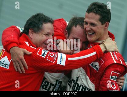 (Afp) - L'Allemand Michael Schumacher, pilote de formule 1 de Ferrari (R) célèbre avec son coéquipier Rubens Barrichello du Brésil (C) et Jean Todt (L) après remportant le titre de champion du monde après la formule un Grand Prix du Japon à Suzuka, le 12 octobre 2003. Schumacher placé 8e, remportant Banque D'Images