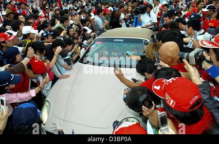 (Afp) - L'Allemand pilote de Formule 1 Michael Schumacher dans sa Maserati tente de faire son chemin à travers une foule de fans comme il arrive sur la piste de course pour la Formule Un Grand Prix du Japon à Suzuka, le 12 octobre 2003. Schumacher placé 8e, remportant un Sixième titre mondial de l'enregistrement. Banque D'Images