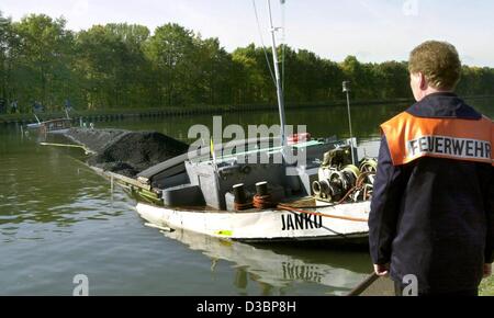 (Afp) - Un pompier se situe sur les rives du canal Mittelland et regarde le navire de fret charbon irrécupérables à Minden, en Allemagne, le 13 octobre 2003. Le navire s'est écrasé ce matin dans le brouillard avec le navire 'Ronaris Hollandaise de fret", a coulé, et maintenant l'ensemble de blocs de détroit de la canal. Le canal est resté clo Banque D'Images