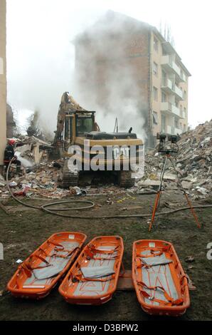 (Afp) - les civières sont devant le site de l'accident tandis qu'un digger supprime les débris à Mulhouse, France, 27 décembre 2004. Une explosion de gaz détruit un bloc d'appartements à Mulhouse le 26 décembre 2004. Au moins 14 personnes ont été tuées lors de l'explosion. L'explosion a probablement été causée par un g Banque D'Images