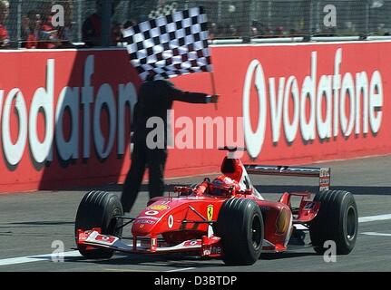 (Afp) - L'Allemand Michael Schumacher, pilote de formule 1 de Ferrari passe la ligne d'arrivée et remporte le Grand Prix d'Italie à Monza, le 14 septembre 2003. Schumacher mène désormais au classement général avec 82 points.