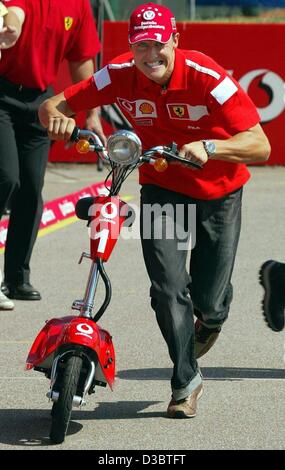 (Afp) - L'Allemand Michael Schumacher, pilote de formule 1 de Ferrari pousse son scooter dans le paddock sur la piste de course à Monza, Italie, le 11 septembre 2003. Le Grand Prix d'Italie aura lieu à Monza le dimanche 14 septembre.
