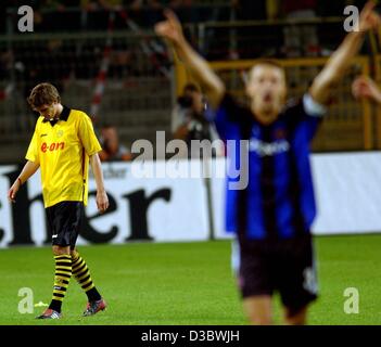 (Afp) - Dortmund's Sebastian Kehl (L) accroche sa tête alors que le joueur de Bruges Timmy Simons (R) cheers après la qualification de la Ligue des Champions contre Borussia Dortmund et FC Bruges club de football belge à Dortmund, en Allemagne, le 27 août 2003. Dortmund a perdu 4-2 après penalty shoot-out et n'a pas réussi à se qualifier Banque D'Images