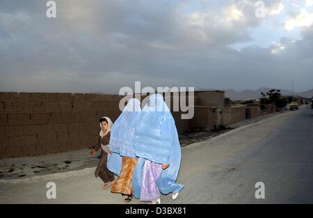 (Afp) - Deux femmes portant le voile burqa bleu traditionnel à pied avec un enfant le long d'une rue à Kaboul, Afghanistan, 4 août 2003. Depuis la chute du régime des Taliban la burqa, qui couvre entièrement la tête et le corps, n'est pas obligatoire pour les femmes en public. Mais les observateurs voient dans le voile en tant qu'indi Banque D'Images