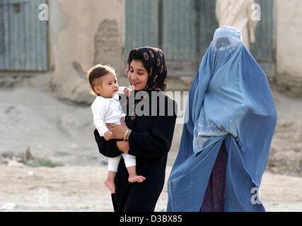 (Afp) - deux femmes, l'un d'entre eux portant la burqa bleu traditionnel voile, marche avec un enfant le long d'une rue à Kaboul, Afghanistan, 4 août 2003. Depuis la chute du régime des Taliban la burqa, qui couvre entièrement la tête et le corps, n'est pas obligatoire pour les femmes en public. Mais les observateurs voient dans la v Banque D'Images