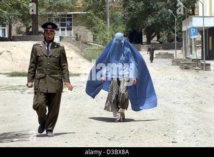 (Afp) - Un colonel de la police afghane est accompagné de sa femme pendant qu'il part l'enceinte de l'académie de police de Kaboul, Afghanistan, 4 août 2003. Comme une tradition, la femme porte le voile burqa bleu et suit son mari avec une distance d'environ deux mètres. Depuis la chute du régime taliban l' Banque D'Images