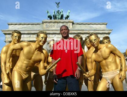 (Afp) - Le sprinter américain Maurice Greene pose avec sept hommes d'Or, les mascottes officielles de l'international stadium festival pour l'athlétisme ISTAF, devant la porte de Brandebourg à Berlin, 8 août 2003. Le quintuple champion du monde et deux fois vainqueur olympique participeront au 4 x 100 m rela Banque D'Images