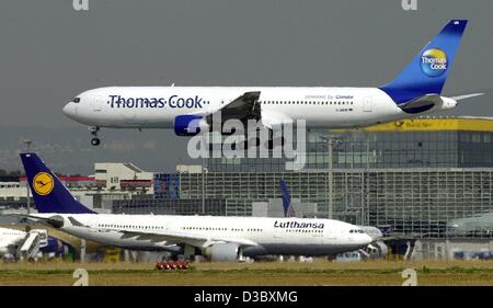 (Afp) - Un Boeing 757 de la Thomas Cook Airlines (anciennement Condor) est sur le point d'atterrir à l'aéroport de Francfort, le 8 août 2003. Dans l'arrière-plan d'un avion de la Lufthansa, la compagnie mère de Thomas Cook Airlines. Banque D'Images