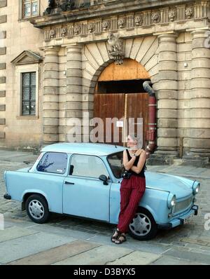 (Afp) - une jeune femme s'appuie sur un bébé de l'Allemagne de l'est bleu automobile Trabant, surnommé 'Trabi" par le grand public, à Dresde, Allemagne de l'Est, 20 juillet 2003. Le peu de voitures allemandes de l'Est de l'ex-RDA sont toujours un favori des fans de voiture et de collectionneurs de voitures. Banque D'Images