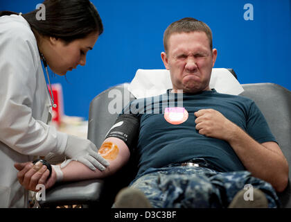 Matelot de la Marine américaine Sean Perkins grimaces qu'il fait un don de sang pendant une croix rouge sang à l'entraînement Naval Weapons Station Seal Beach le 13 février 2013 à Seal Beach, en Californie. Banque D'Images