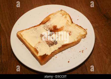 Tranche de pain beurrée on white plate Banque D'Images